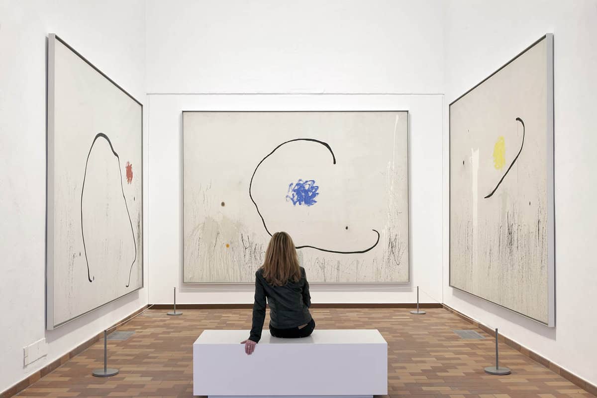 Interior gallery with a single woman staring at several artwork