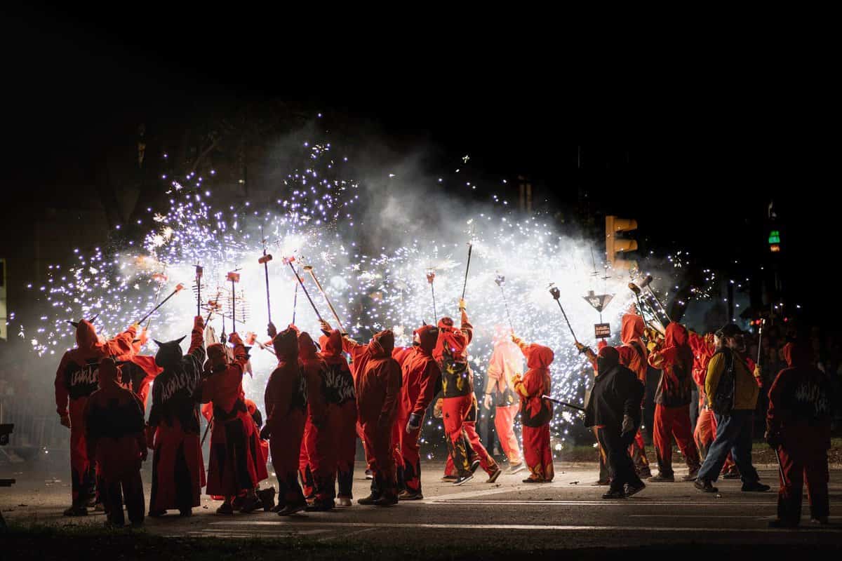 Group of people in street dressed in red hooded uniforms showering sparklers everywhere