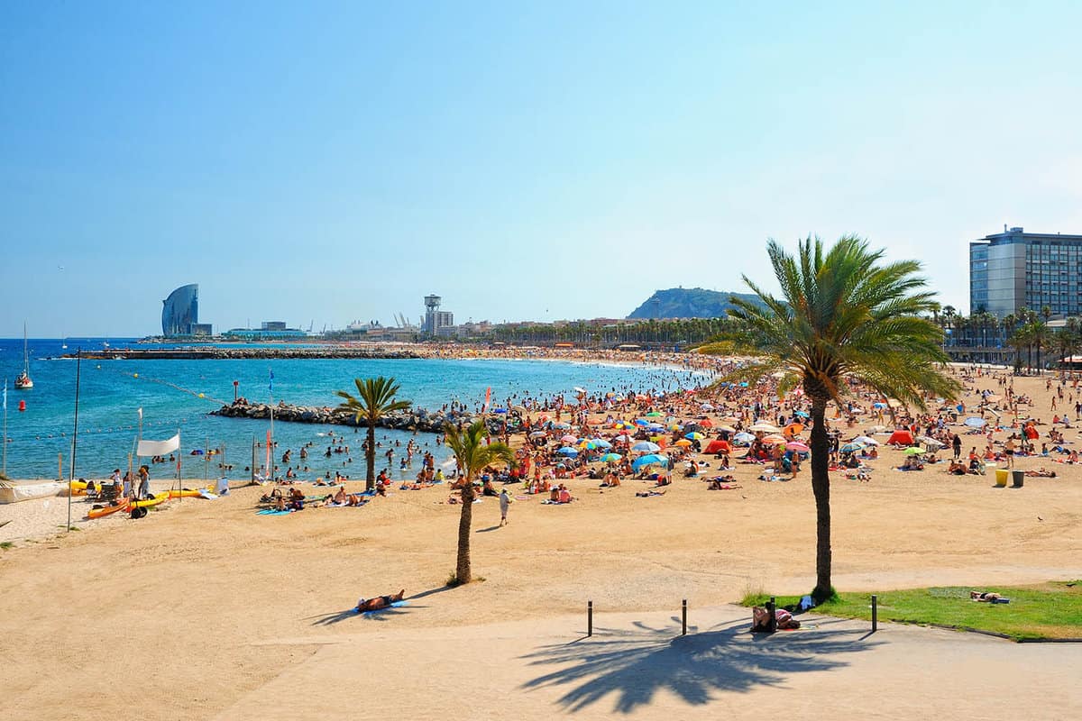 View of a golden beach with alot of people and colourful umbrellas