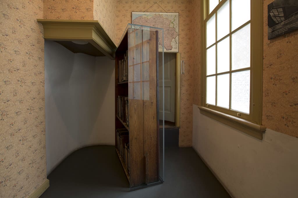 Photo of a large bookcase as a door in a room, with a secret closet behind it