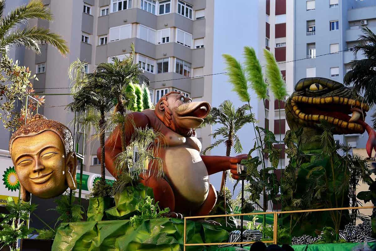 Parade float with large depictions of a dinosaur, an orangutan, and a face of Buddha