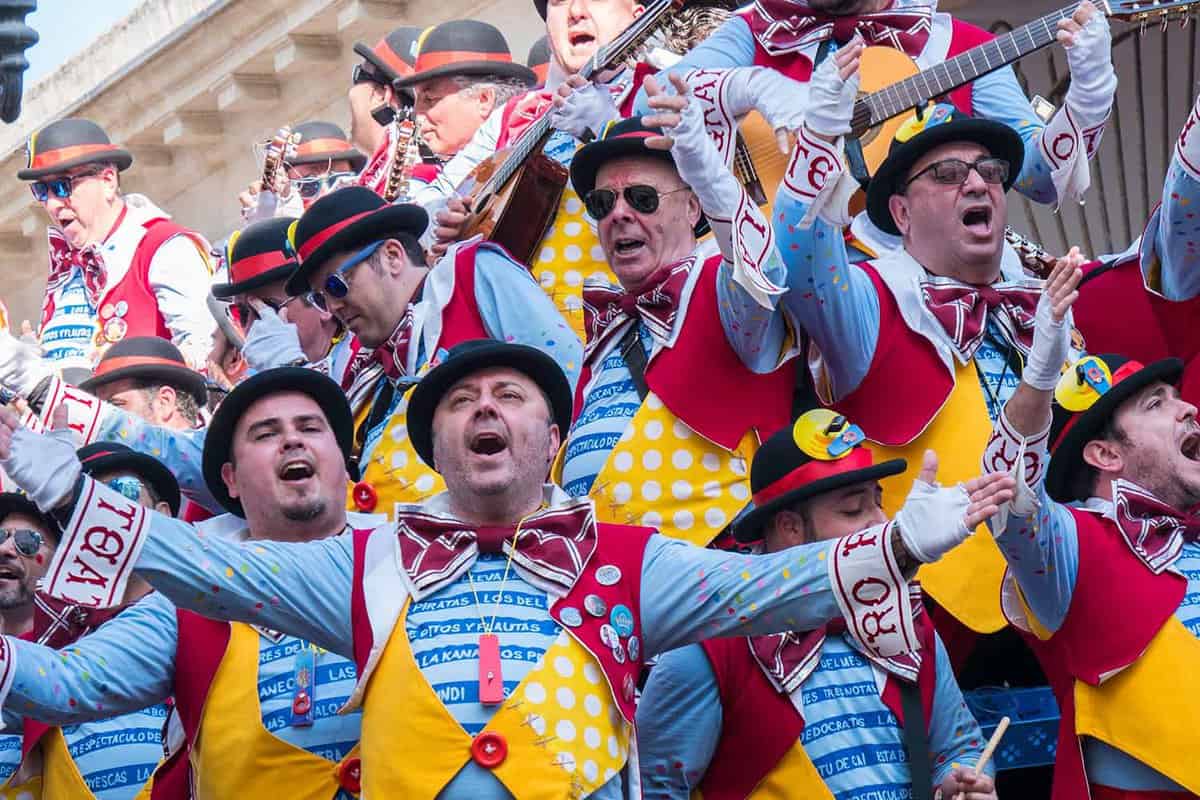 Men dressed in matching colourful outfits sing and play instruments