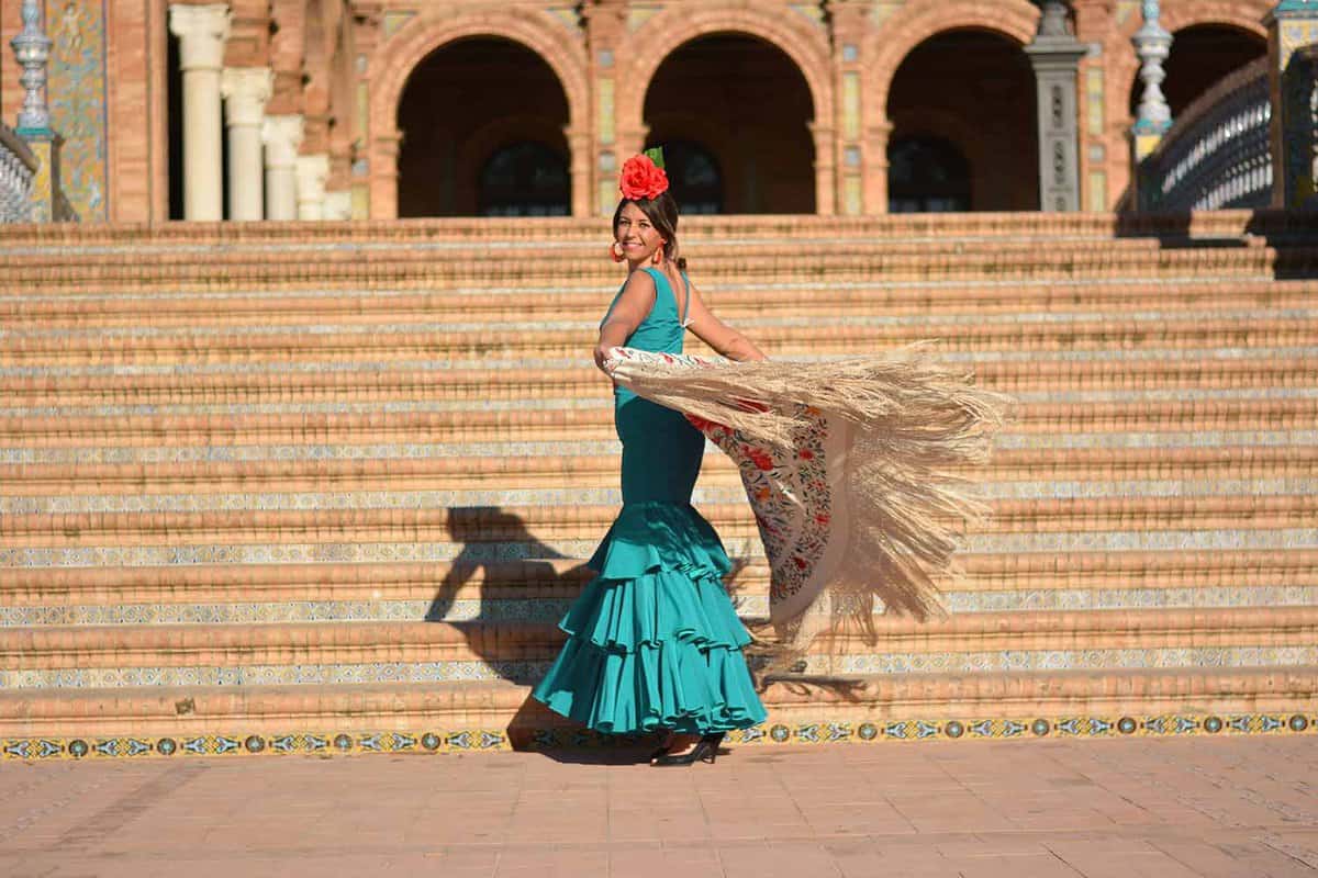 A woman wearing flamenco dress twirls in front of a set of steps