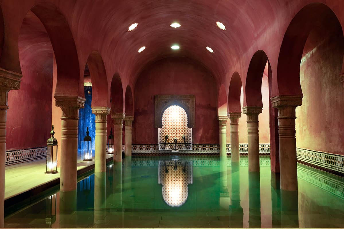 A green tiled pool surrounded by arches with a curved ceiling
