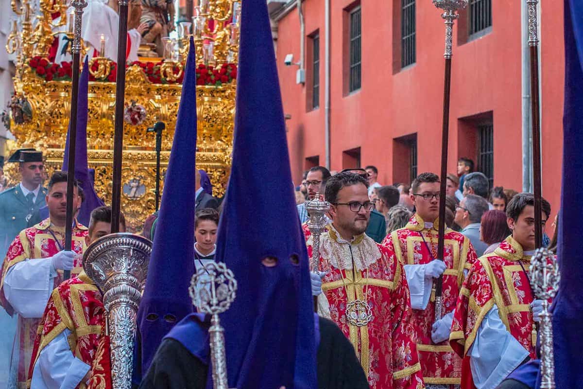 Close up of people in a processions, several wearing pointed purple hoods