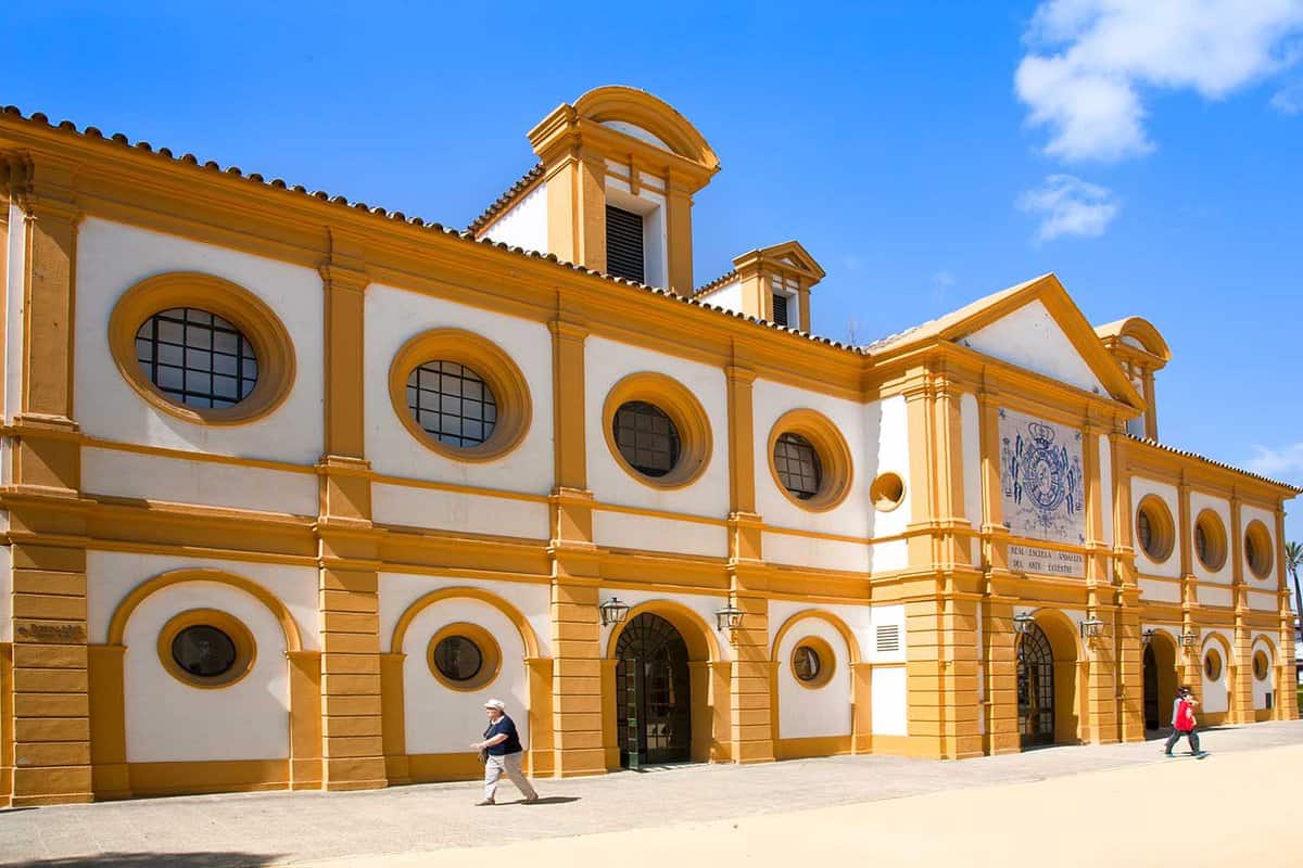 Exterior of the school, a white building with mustard trim