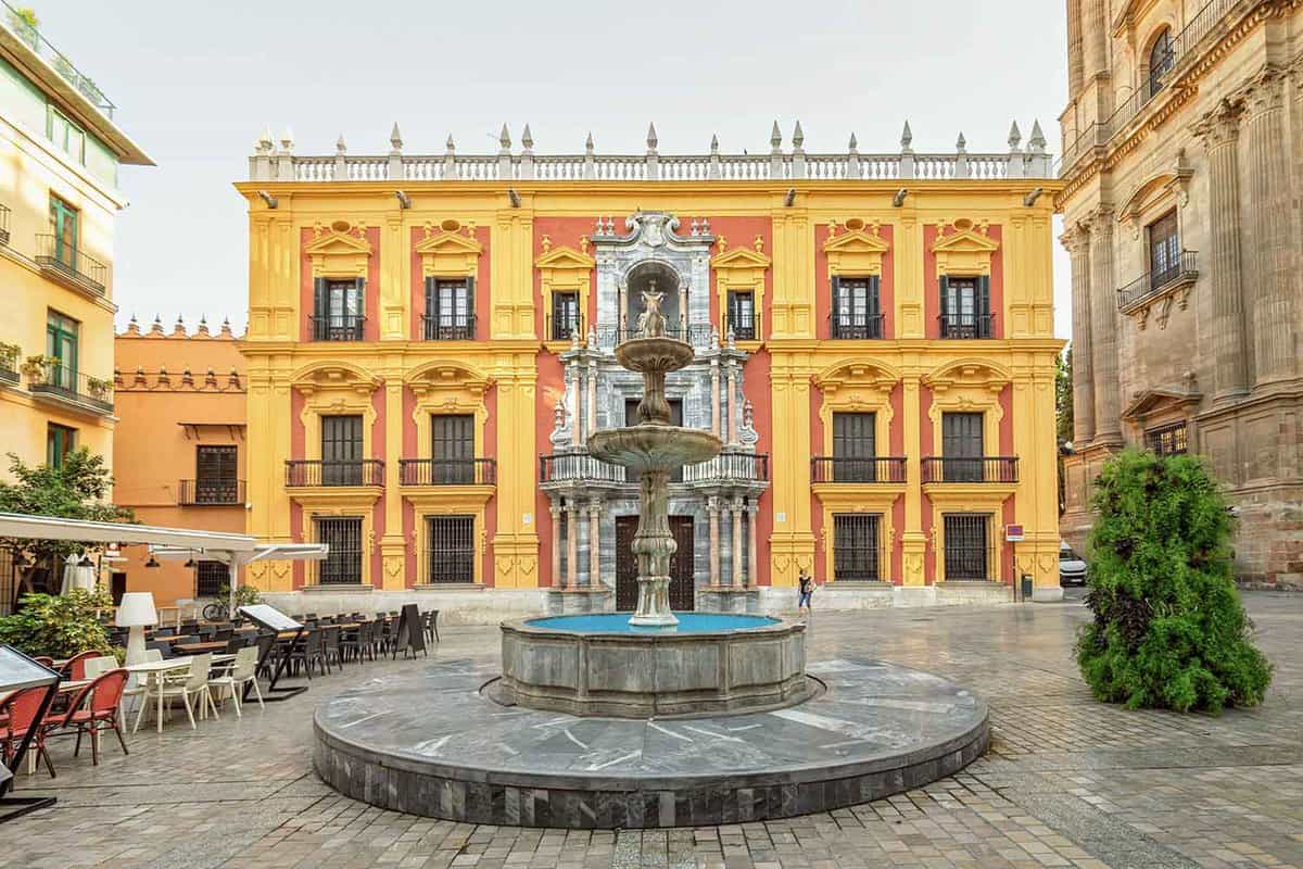 A small sqaure with central fountain, backed by a beautifully-decorated yellow and red municipal building