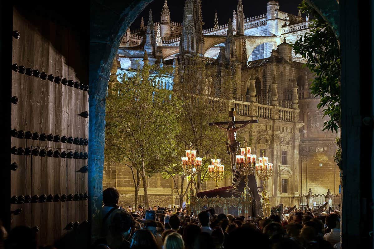 View of a crowd looking at the procession of a statue of Jesus' crucifixion at dusk