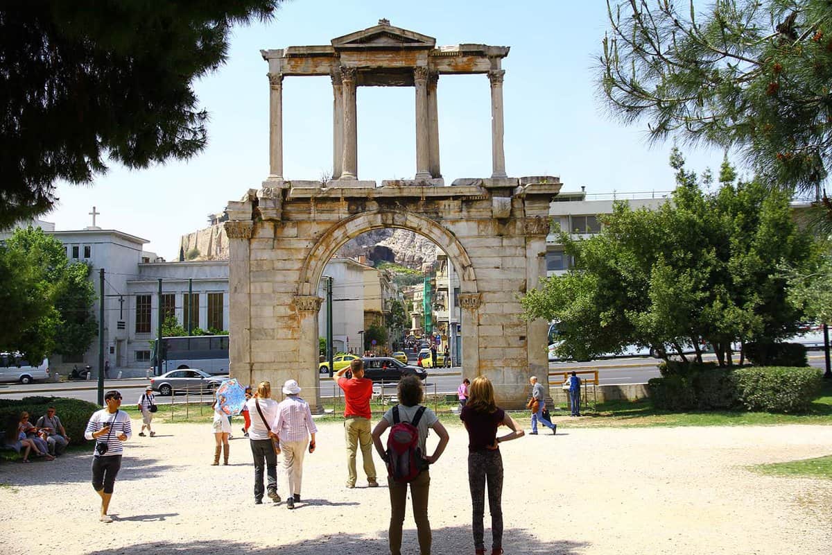 Tourists stand and admire the Corinthian columns of Hadrians Arch