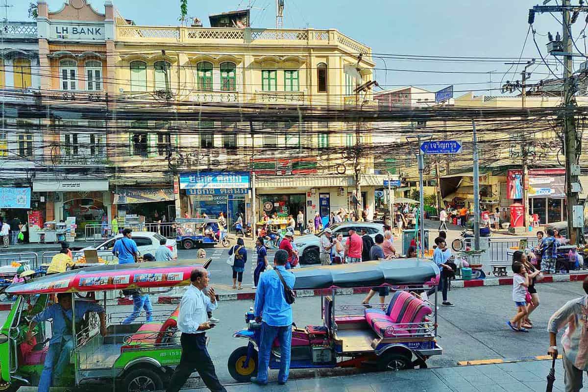 A bustling road with a historical building in the background and tuktuks in the foreground