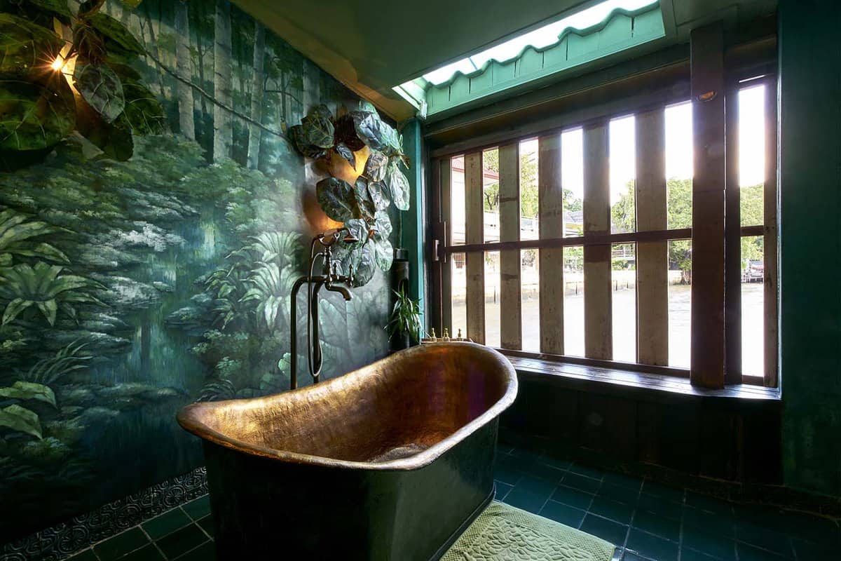 Bathroom with copper tub and wall painted with leaves