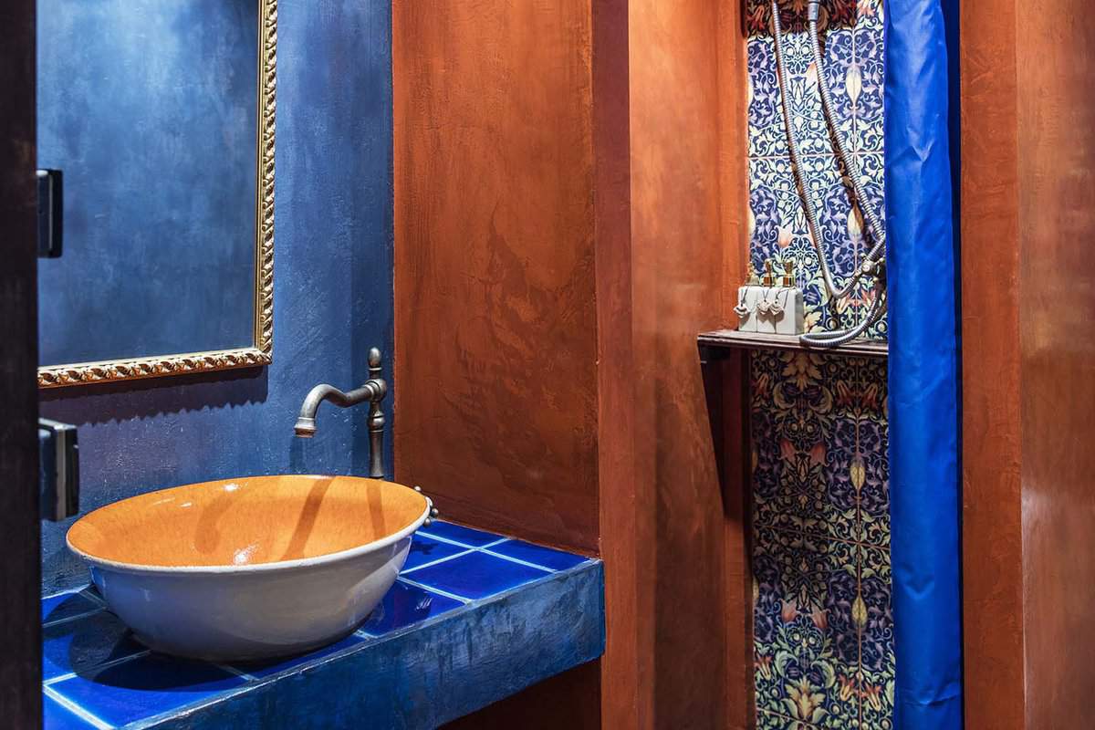 Bathroom with blue and orange walls, colourful tiles, and an orange sink