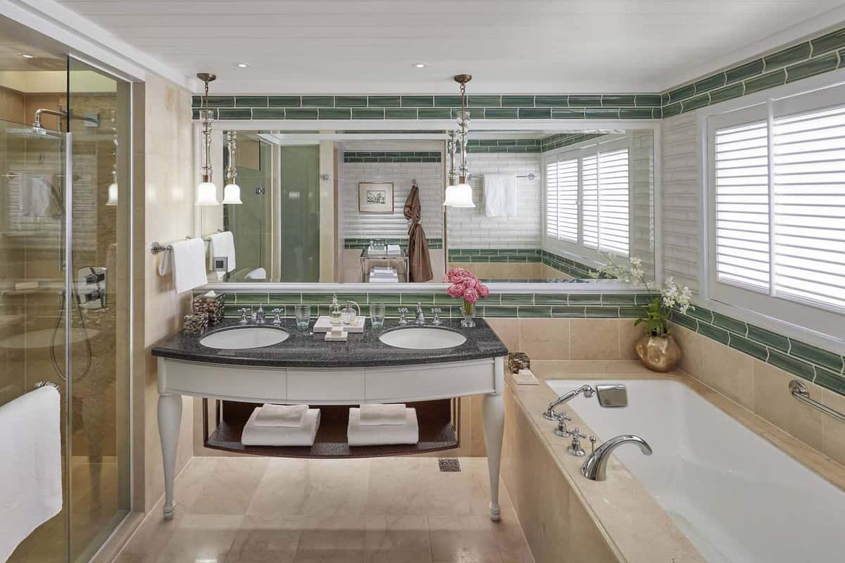Stylish tiled bathroom with two sinks and large bathtub