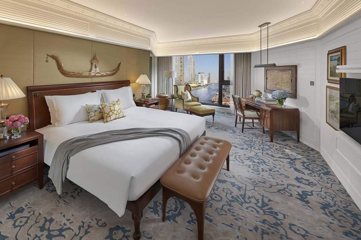 Large bedroom with a long leather stool and a river view