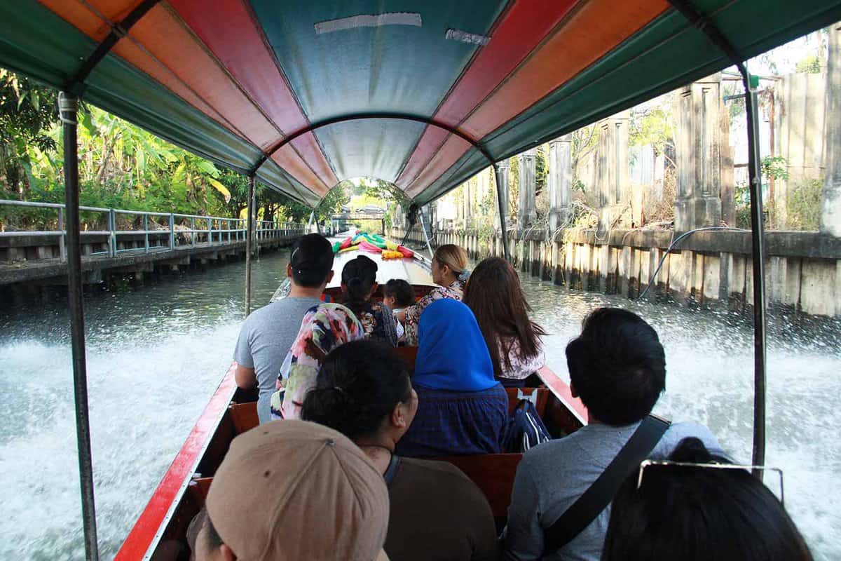 Passengers in a long tailed boat in the canal