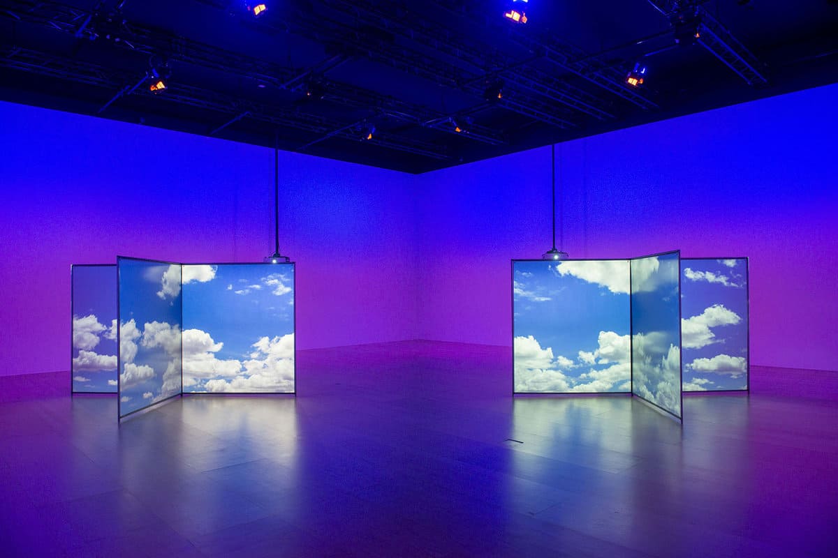 Empty exhibition room except for two cubes with clouds on