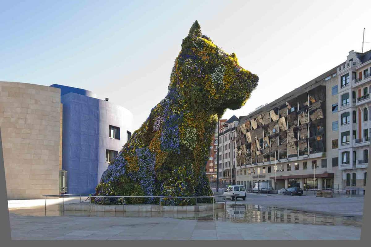 dog sculpture covered in plants sitting in an empty square