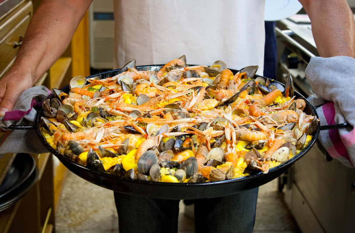 dish of prawn paella held by waiter