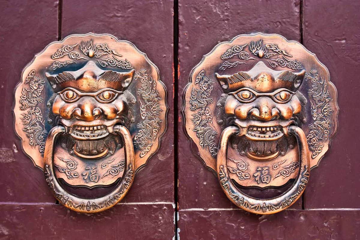 Close up of two ornate brass door knockers in a hutong