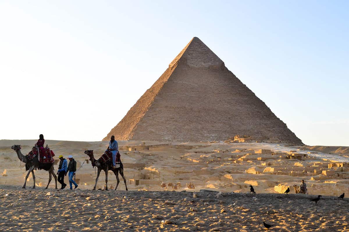 Local men on camels passing infront of some pyramids