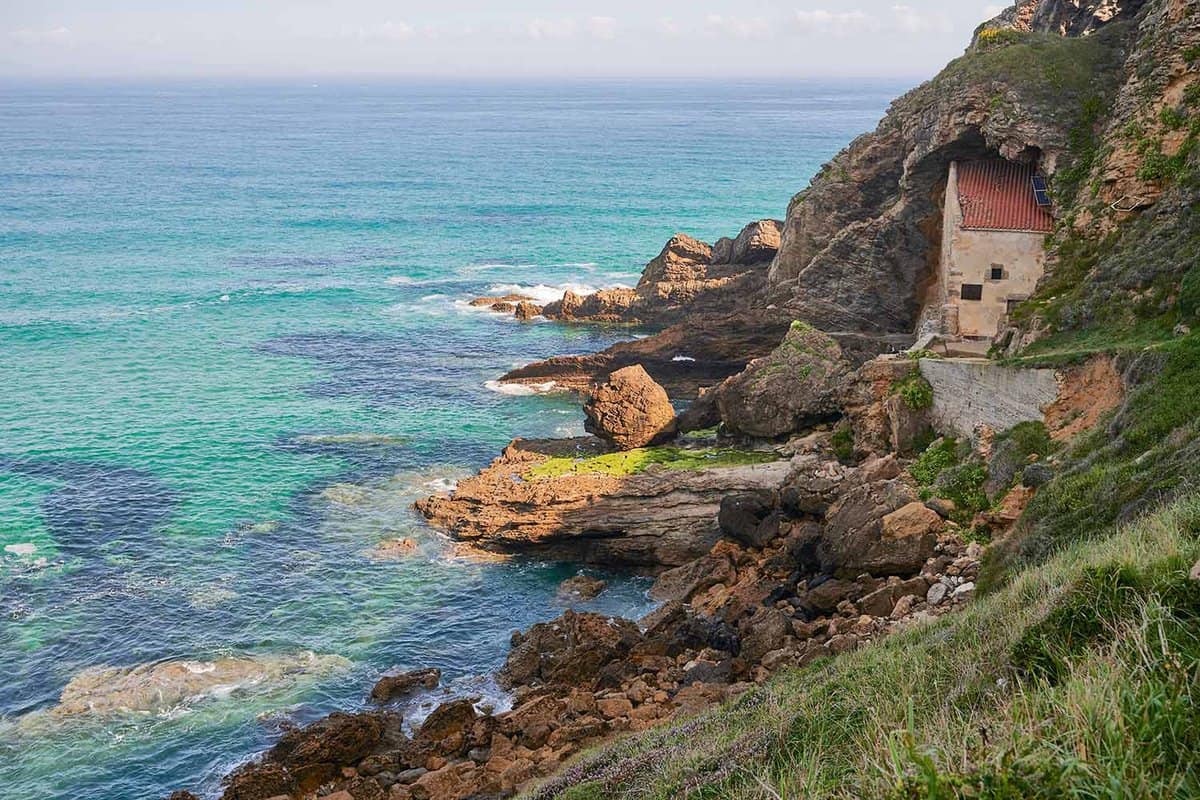 View of the small house tucked into the cliffs by the sea