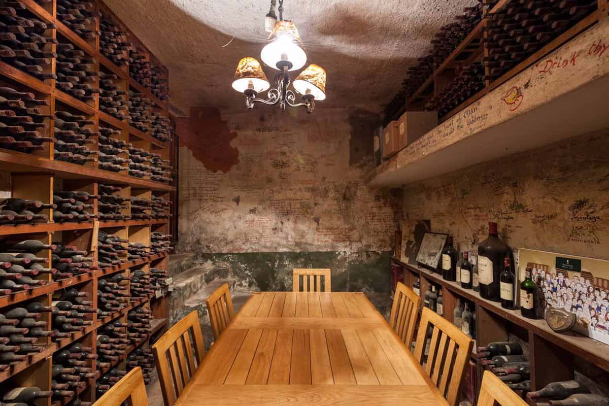 Tasting room, with a table and chairs and alot of wine bottles on shelves
