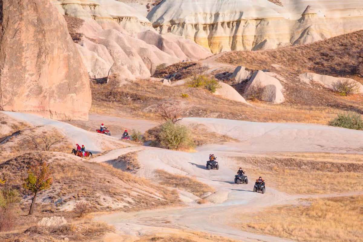 Three people biking up a mountain with a mountain in the background.