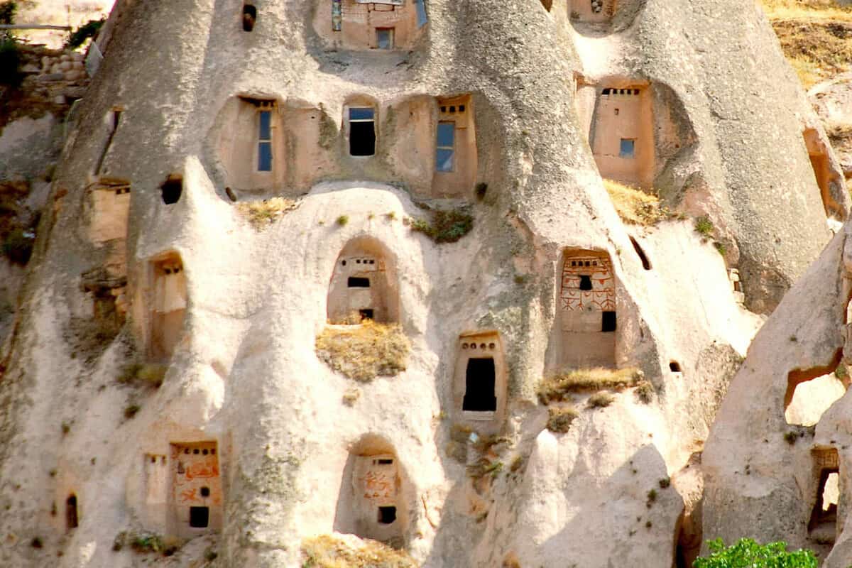 A focky mountain with many carved out doors in it.