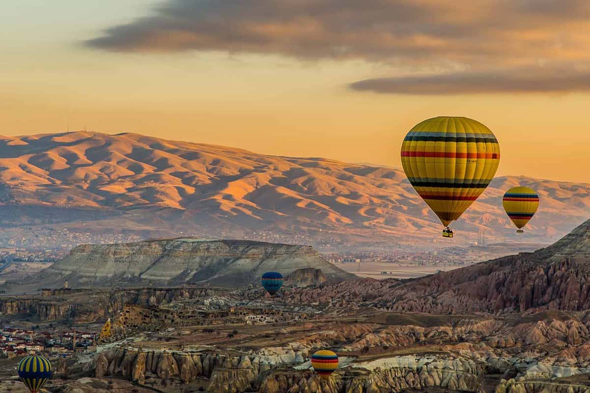 2 Hot air balloons at sunset with a mountainous landscape