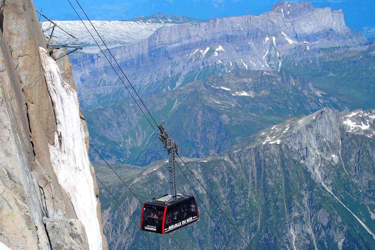 Cable car cabin on AIGUILLE DU MIDI in highest french alpine mountains range with rocky slope and scenic ALPS landscape view in warm sunny summer day