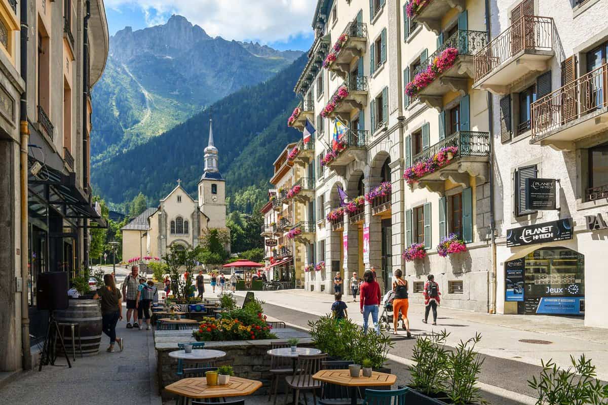 Glimpse of the historic centre of the Alpine town with the church of Saint-Michel, sidewalk café and tourists in summer