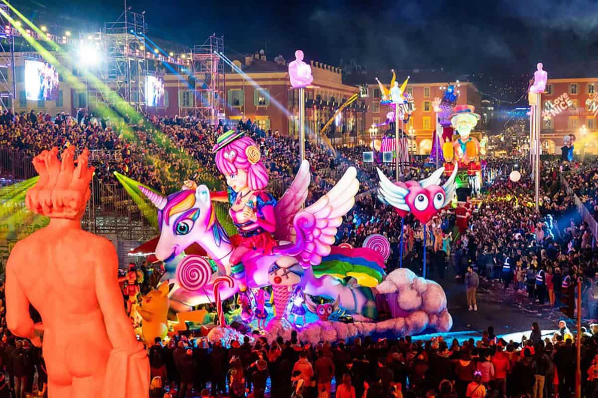 Brightly-illuminated carnival float surrounded by crowds