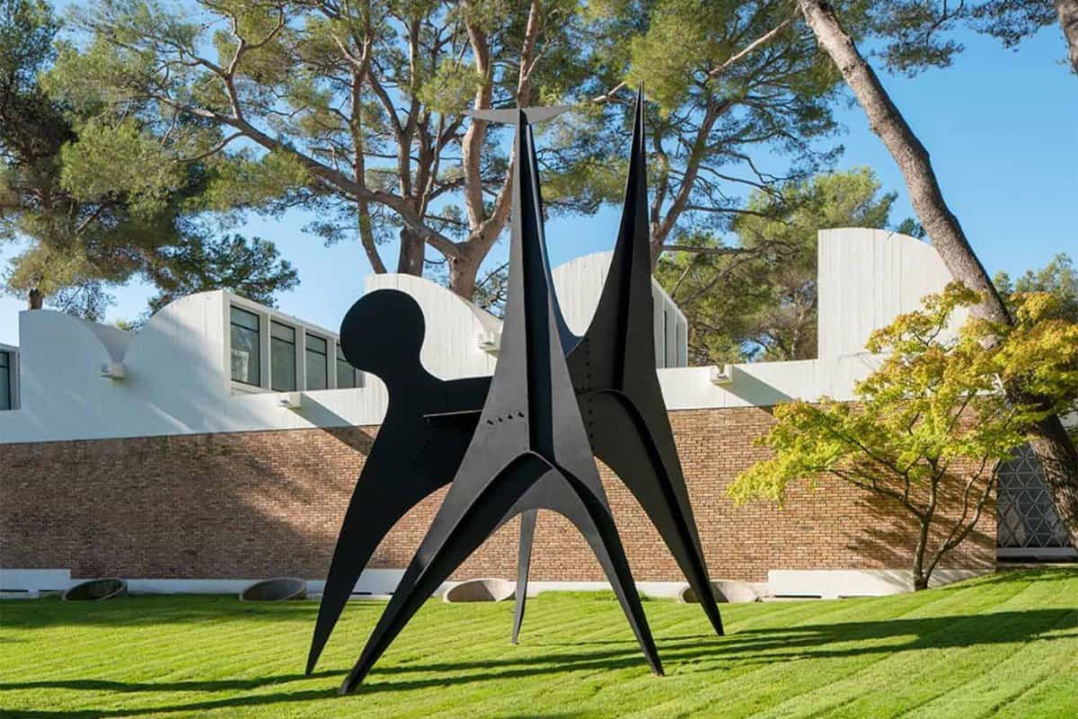 Large, black sculpture on grass in front of museum