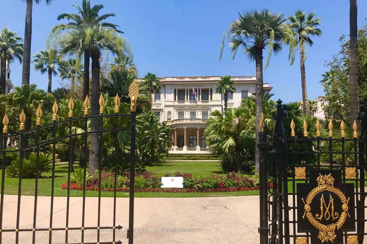 Gated entrance to a palace with palm trees in garden