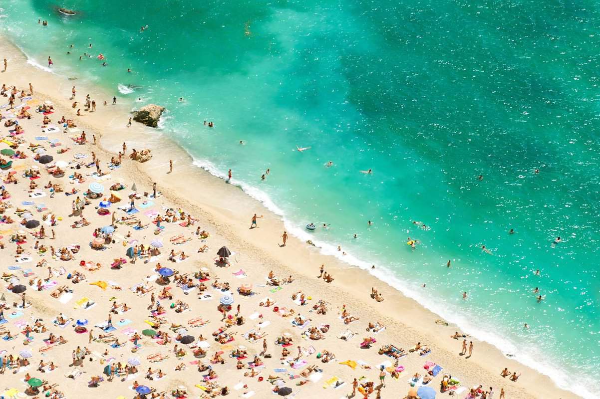 Aerial view of white-sand beach dotted with bathers