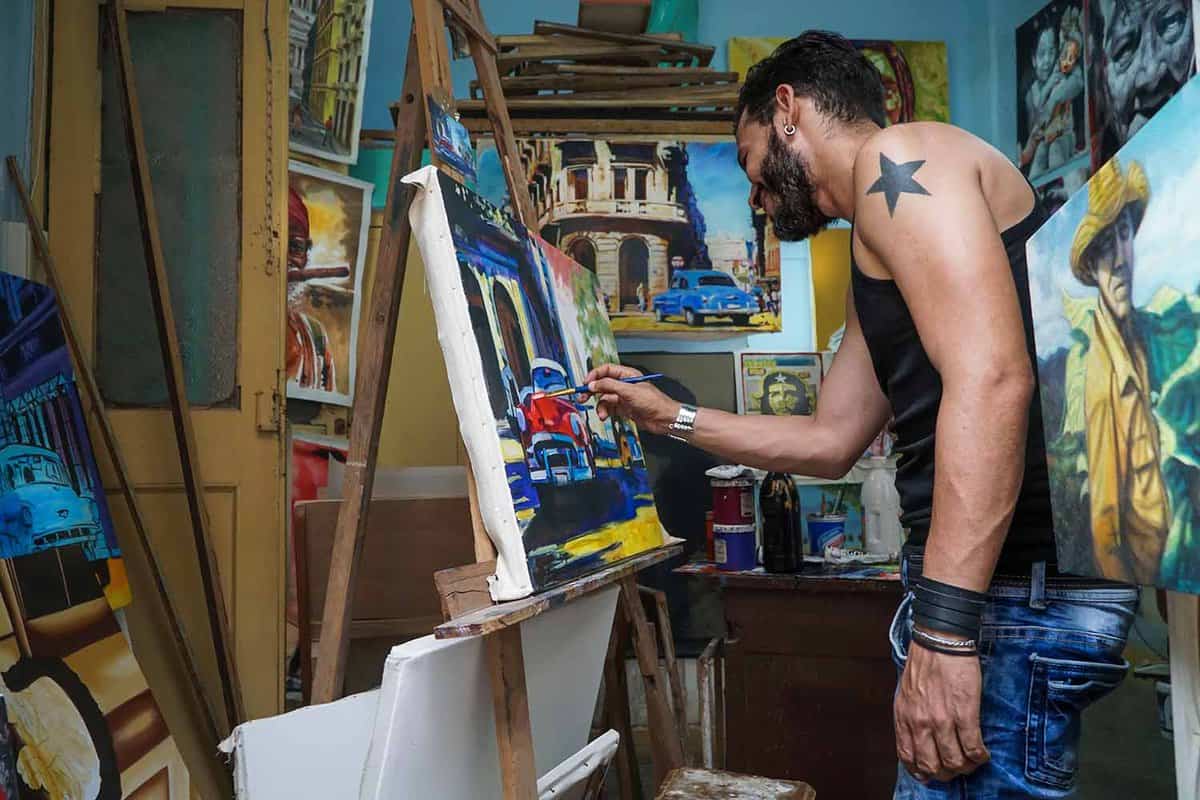 A cuban man in his studio doing paintings to sell as a souvenir