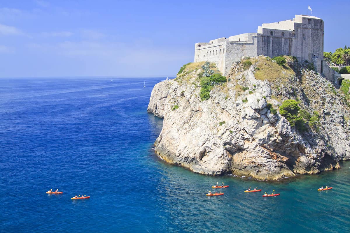 Sea around Dubrovnik with kayaks paddling around the cliffs
