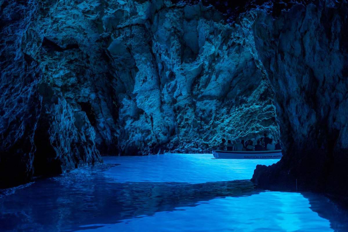 Inside the dark cave with bright blue illuminated water
