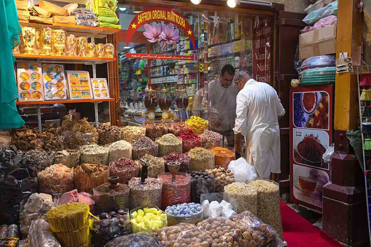 Merchant selling spices to client in Dubai spice souk in Deira district. Traditional spices shop in old town
