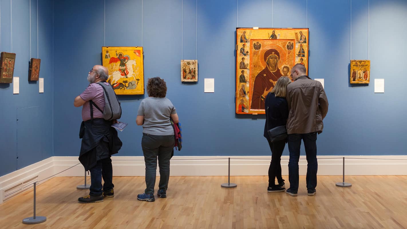 A group of people looking at different paintings inside the National Gallery of Ireland