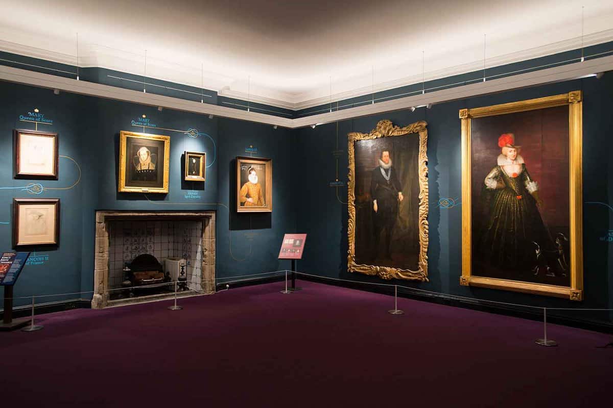 Dark-walled room showing large portraits in gold frames