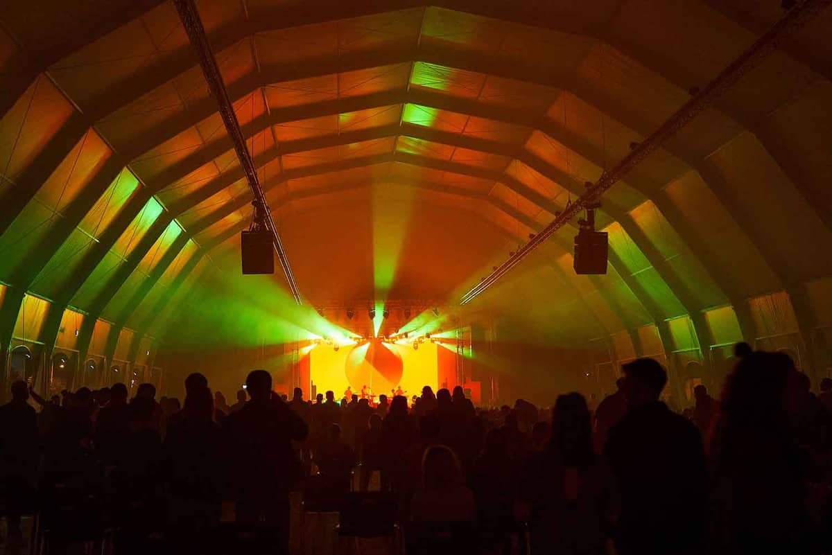 Darkened dance hall with band playing on stage, green and yellow illuminating lights