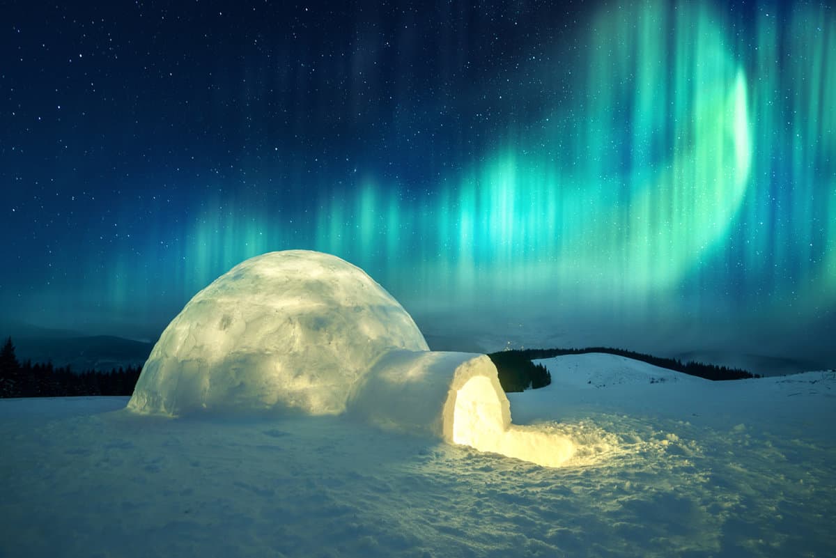 real igloo lit from within with northern lights in sky behind