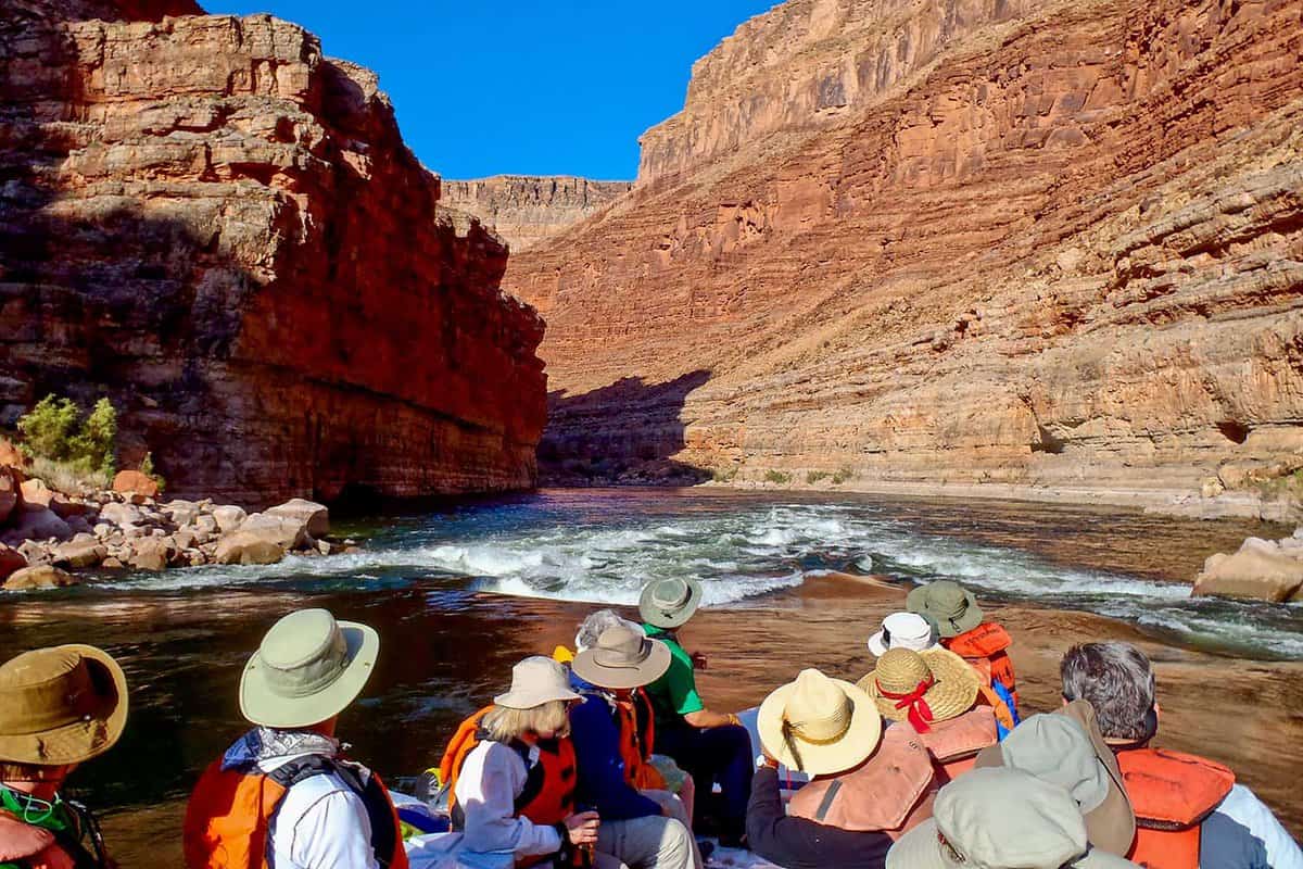 Group of tourists on a raft staring down at rapids in the Grand Canyon