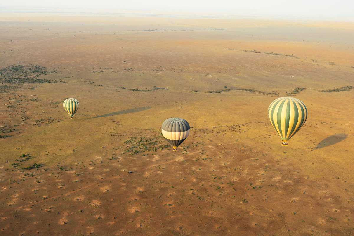 aerial view of 3 hot air balloons drifting over the landscape