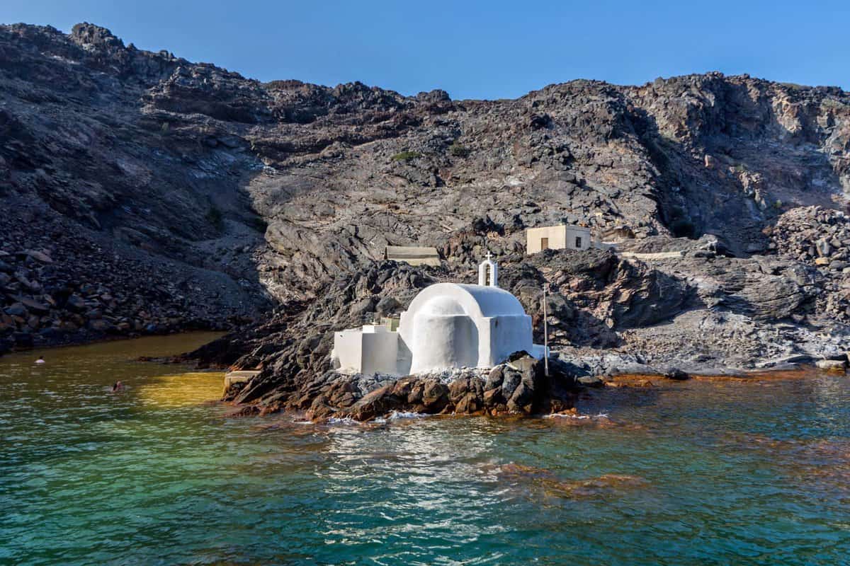 Palaia Kameni, volcanic Greek island, near Santorini, Greece. A tiny traditional church built right on the coast. The sea water is warm due to a hot underwater spring.