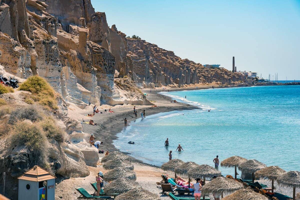 People swimming and sunbathing and sunbathing on the beach near white rocks of Vlychada