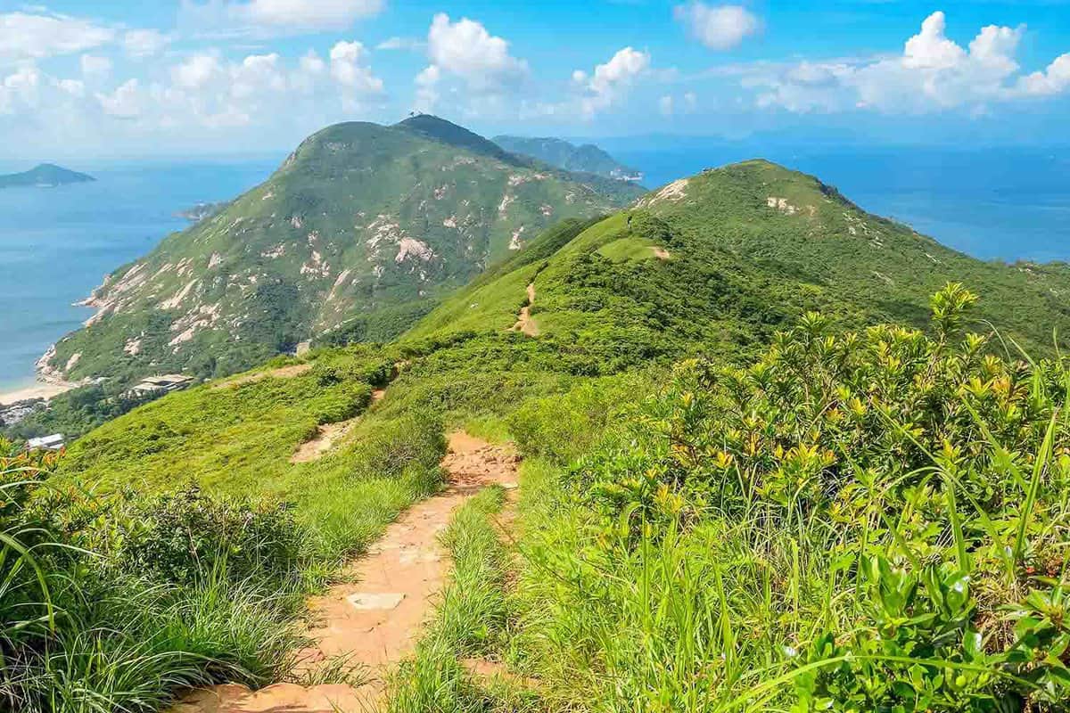 A path leading down rolling green hills with a blue sky above