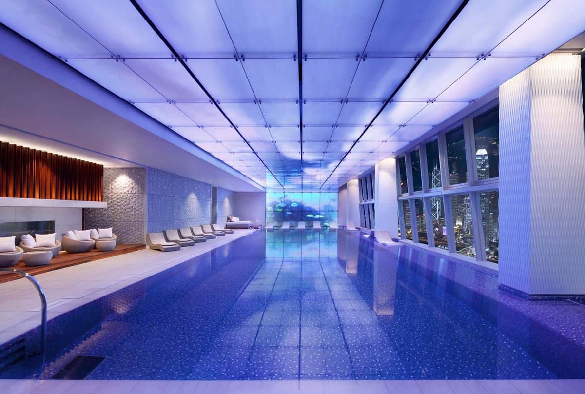 Indoor swimming pool at night with futuristic lighting and lounge beds