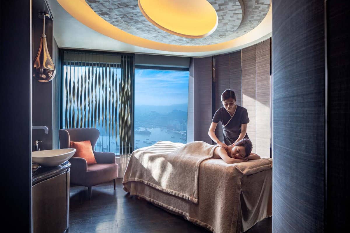 Woman receiving a massage from a masseuse in a room with a view of harbour
